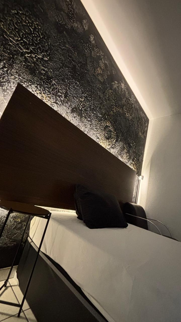 Detalhe da cabeceira com iluminação indireta na suíte da Zarah Massagem